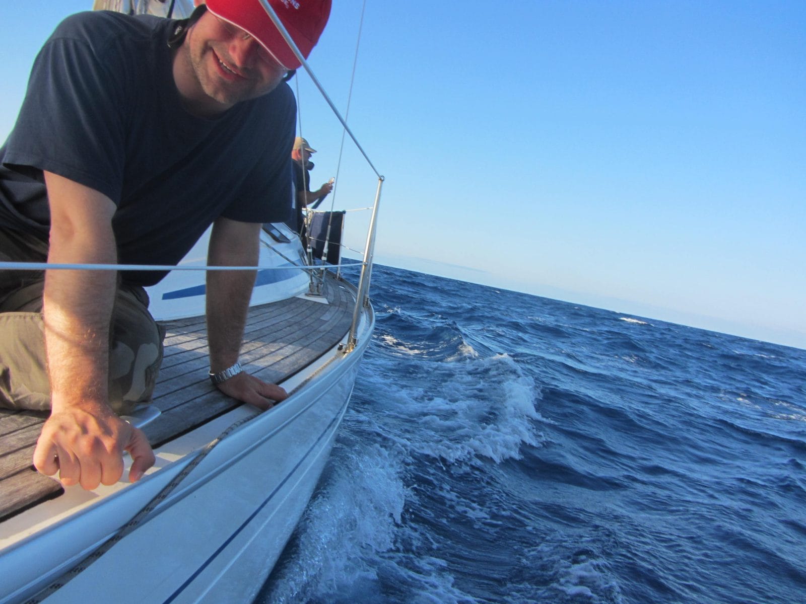 Crew member leaning over the side of the Bavaria 31 to touch the water on the way from Cardiff to Palma