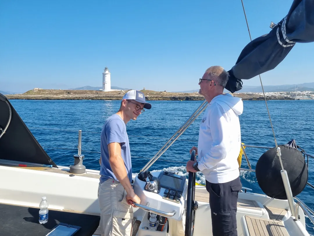 Two crew members at the helm of a Hanse 575 in the Strait of Gibraltar, yacht delivery June 2026 Two crew members at the helm of a Hanse 575 in the Strait of Gibraltar, yacht delivery June 2026