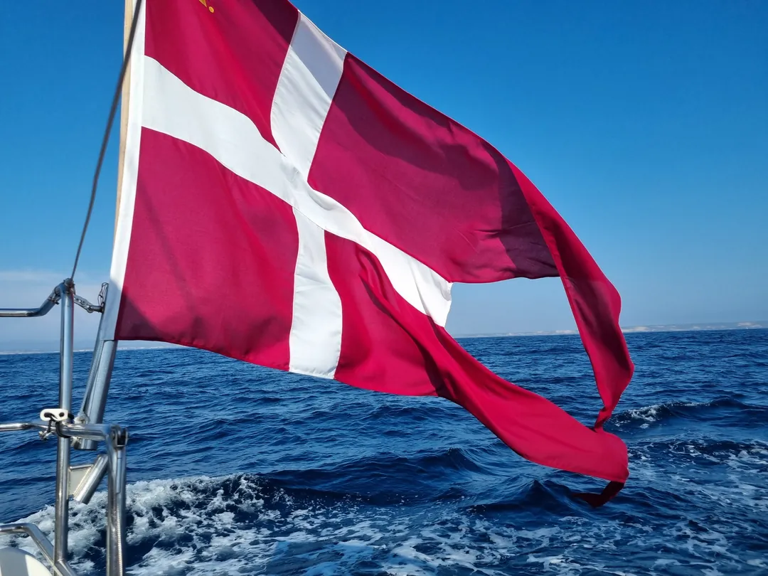 Danish ensign flying from the stern of a Hanse 575 at sea, yacht delivery 2026 Danish ensign flying from the stern of a Hanse 575 at sea, yacht delivery 2026
